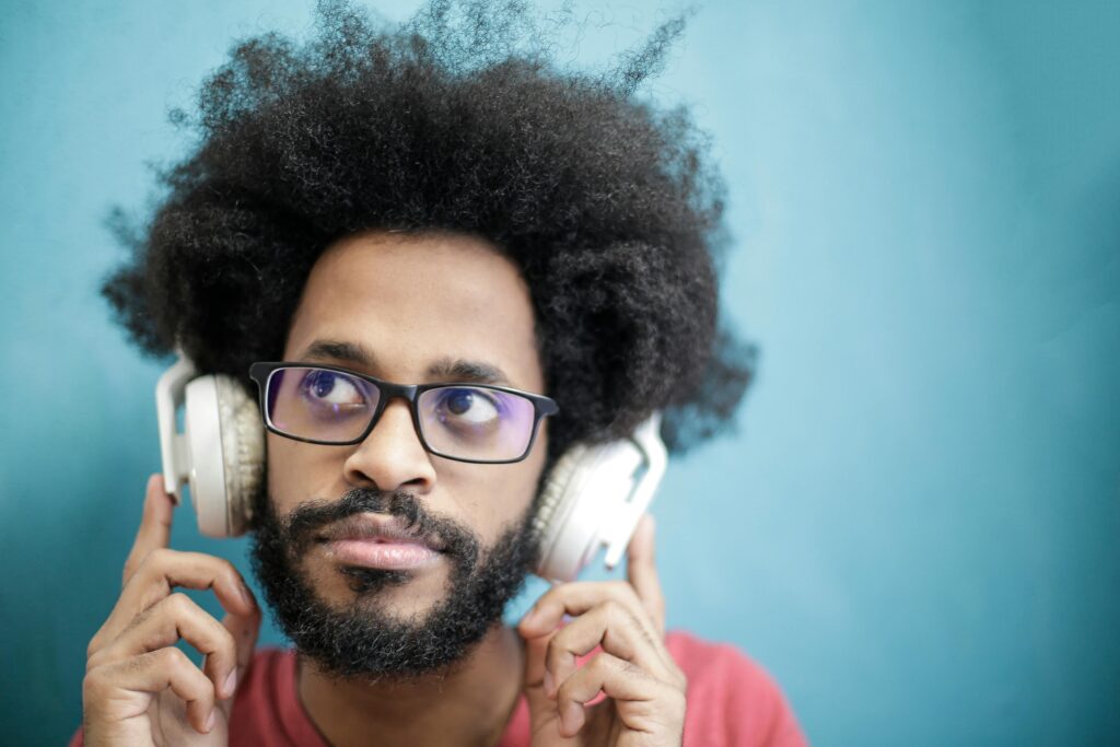 Home Portrait of a man with afro hairstyle enjoying music with headphones. Vibrant and stylish.